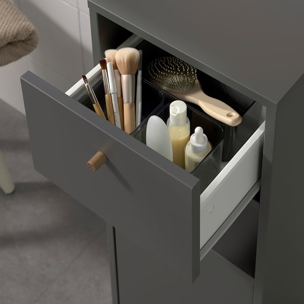 Offener grauer Badezimmerschrank mit Schublade. Bewahrt Toilettenartikel, Bürsten und Flaschen auf.
