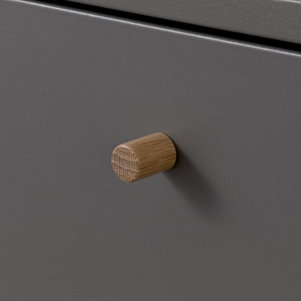 Handgefertigte Holzknöpfe an mattgrauer Schranktür. Abgerundete Form mit sichtbarer Holzmaserung. Stilvolles, langlebiges und funktionales Design.