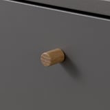 Handgefertigte Holzknöpfe an mattgrauer Schranktür. Abgerundete Form mit sichtbarer Holzmaserung. Stilvolles, langlebiges und funktionales Design.