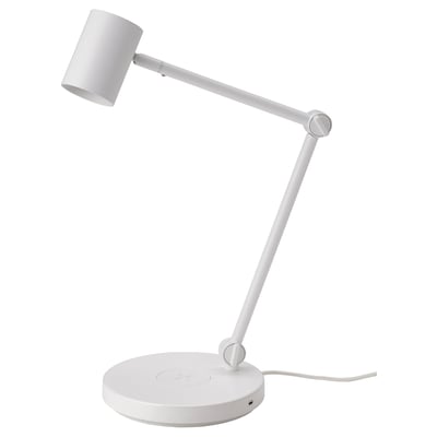 Eine weiße NYMÅNE Tischleuchte mit verstellbarem Arm und kabellosem Ladegerät auf dem Sockel.
