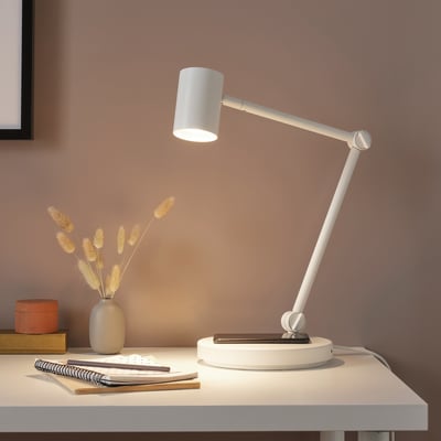 Moderne weiße Schreibtischlampe mit verstellbarem Arm, Blumen und Notizbuch.