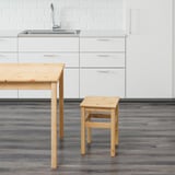 Küchenhocker aus Holz neben Tisch und Spüle.