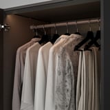Schrank mit LED-Lichtstreifen, die Kleidung auf Kleiderbügeln beleuchten.