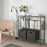 Grünes Metallregal mit Büchern, Pflanze, Kisten, Stuhl, Lampe
