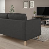 Modernes Wohnzimmer: graues PÄRUP-Sofa, Flachbildfernseher, heller Holzboden, Pflanze, Kunstdrucke, Teppich.