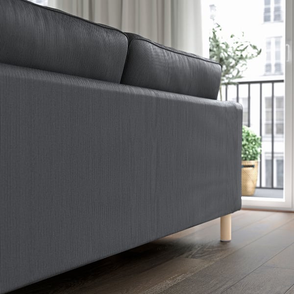 Modernes graues Sofa mit schlankem Design und hellen Holzbeinen in der Nähe eines Balkons.
