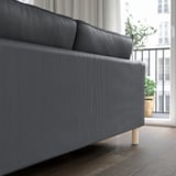 Modernes graues Sofa mit schlankem Design und hellen Holzbeinen in der Nähe eines Balkons.