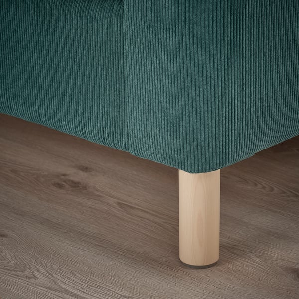 Nahaufnahme eines modernen, blaugrünen Sofas mit schlanken, hellen Holzbeinen auf einem Holzboden, das sein hochwertiges Design und seine hochwertigen Materialien zur Geltung bringt.