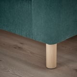 Nahaufnahme eines modernen, blaugrünen Sofas mit schlanken, hellen Holzbeinen auf einem Holzboden, das sein hochwertiges Design und seine hochwertigen Materialien zur Geltung bringt.