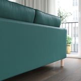 Blaugrünes Sofa in der Nähe des Fensters mit Topfpflanze, abnehmbarem, maschinenwaschbarem Bezug und Holzbeinen.