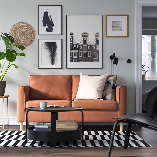 Modernes Wohnzimmer mit braun gestreiftem Sofa, schwarzem Couchtisch und grüner Pflanze.