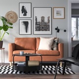 Modernes Wohnzimmer mit braun gestreiftem Sofa, schwarzem Couchtisch und grüner Pflanze.