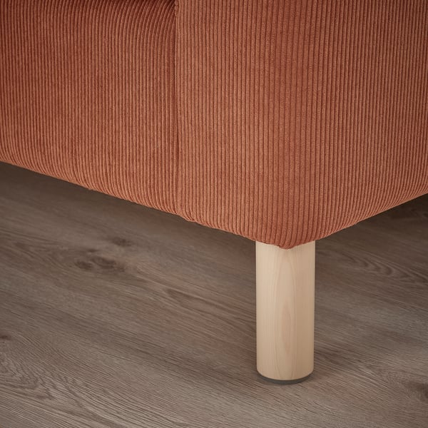 Eine Nahaufnahme eines modernen Sofas, eines Beins und eines Kissens. Das Bein aus Naturholz trägt ein weiches, strukturiertes Kissen und zeichnet sich durch hochwertiges Design und Komfort aus.