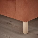 Eine Nahaufnahme eines modernen Sofas, eines Beins und eines Kissens. Das Bein aus Naturholz trägt ein weiches, strukturiertes Kissen und zeichnet sich durch hochwertiges Design und Komfort aus.