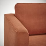 Nahaufnahme eines orangefarbenen gepolsterten Sofas mit gerippter Textur mit sauberen Nähten und bequemen Kissen.