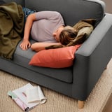 Frau schläft auf grauem PÄRUP-Sofa mit abnehmbarem Bezug, das zum Entspannen einlädt.