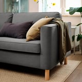 Ein gemütliches graues Sofa, geschmückt mit weichen Kissen und einem drapierten Überwurf, lädt zum Entspannen ein.