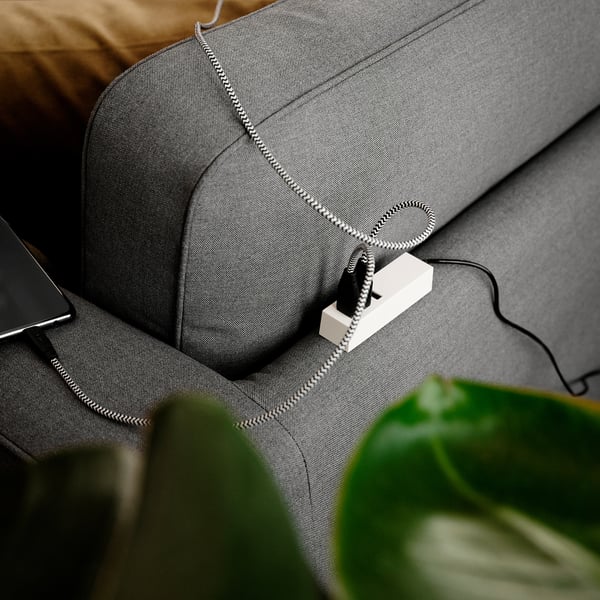 Ein modernes Sofa mit abnehmbarem, waschbarem Bezug und Taschenfederkernsitzen, das Komfort und Pflegeleichtigkeit beweist. Laptop ruht auf Arm, Pflanze in der Nähe.
