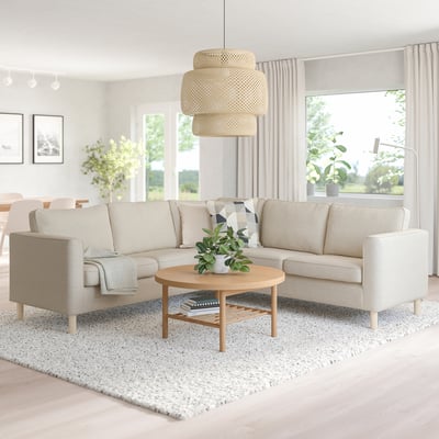 Modernes Wohnzimmer mit cremefarbenem Sektionssofa PÄRUP, Couchtisch aus Holz, Pendelleuchte aus Korbgeflecht und großem Fenster. Das Sofa bietet Platz für viele.