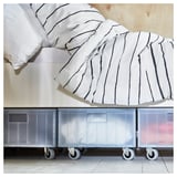Eine durchsichtige Aufbewahrungsbox aus Kunststoff mit Rädern, ideal zum Organisieren von Gegenständen, hergestellt aus recyceltem Kunststoff, mit einem Deckel, der fest an Ort und Stelle sitzt.