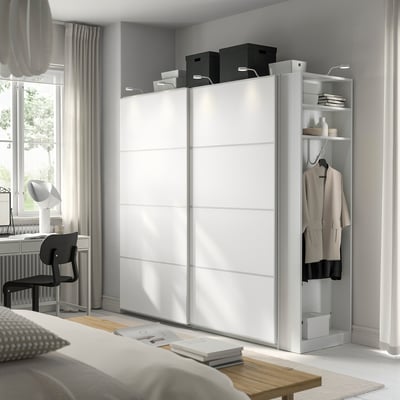 Der moderne weiße PAX-Schrank mit Kleiderstange und Regalen fügt sich nahtlos in das Dekor ein und bietet Stauraum, ohne zu überwältigen.