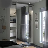 Modernes Schlafzimmer mit verspiegeltem PAX-Kleiderschrank, organisierter Kleidung und durchsichtigen Vorhängen.