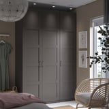 Modernes Schlafzimmer mit grauen PAX-Kleiderschränken, Korbstuhl und Wandkunst.