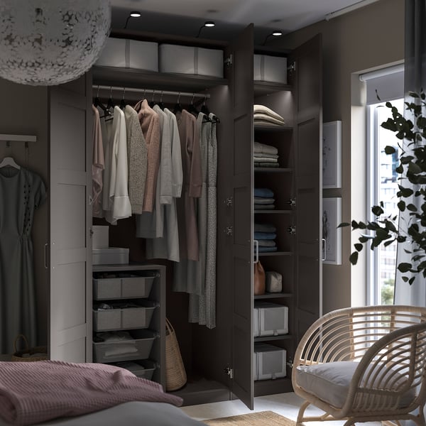 Moderner dunkelgrauer PAX-Kleiderschrank mit Kleidung, Regalen und Korbstuhl.