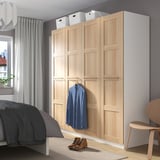 PAX-Schrank an der Wand, blaues Hemd, am Fenster, graues Bett, Stiefel auf dem Boden.