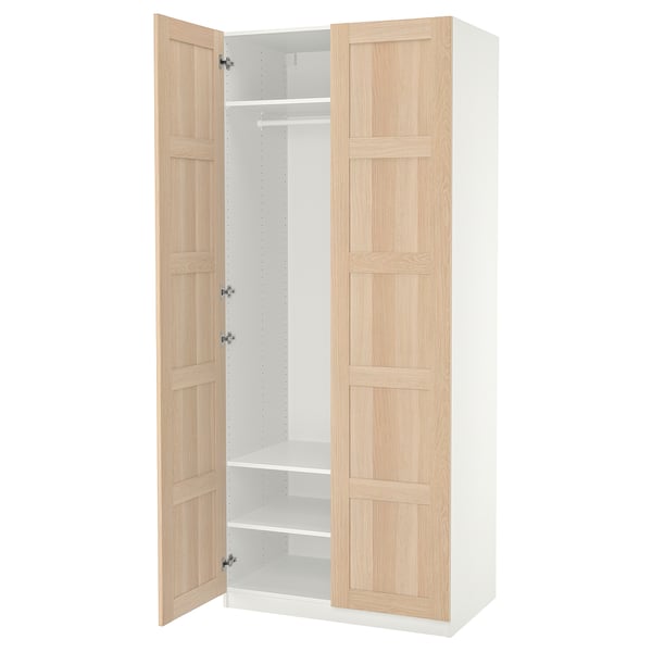 Ikea PAX Kleiderschrank, weiß mit hellen Eichentüren, offen stehend mit Regalen.