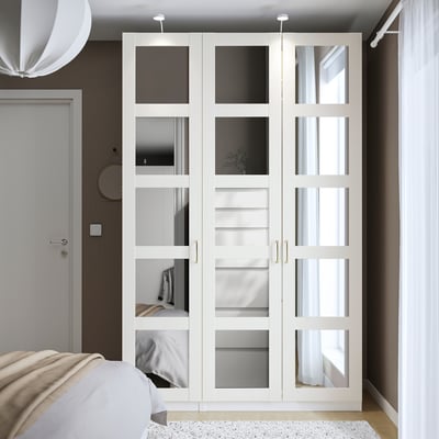 Weißer PAX-Kleiderschrank mit verspiegelten Türen, minimalistisches Design, großes Nebenbett.