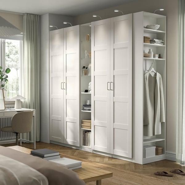 Weißer IKEA PAX Kleiderschrank, hoch mit offenem/geschlossenem Stauraum, Regalen, Hängefläche in hellem Raum.
