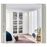 Weißer PAX-Kleiderschrank mit Glastüren und Regalen in minimalistischem Raum