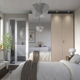 Modernes, neutrales Schlafzimmer mit schwebendem Bett, großem Spiegel, Hängeblumenlampen und eingebautem PAX-Stauraum. Helles, minimalistisches Dekor.