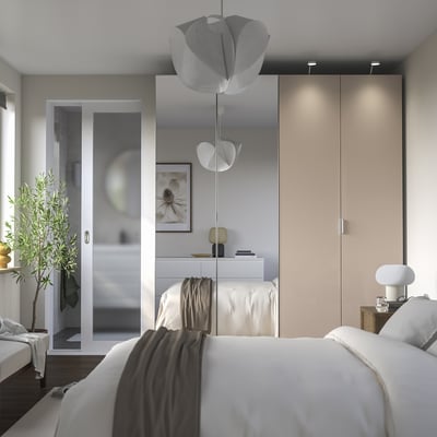 Minimalistischer beigefarbener PAX-Kleiderschrank mit Beleuchtung, zwei Pendelleuchten, Olivenbaum, gemütlichem Bett, verspiegelter Tür und Beistelltisch mit Lampe.