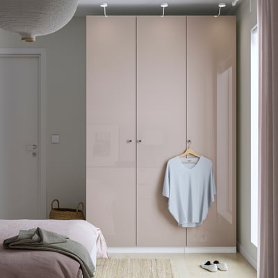 Modernes Schlafzimmer mit hohem hellrosa PAX-Kleiderschrank, Netzkorb mit blauem Hemd.