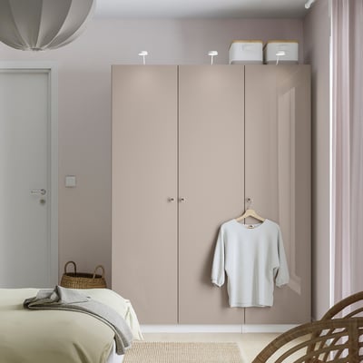 Minimalistisches Schlafzimmer mit beigem PAX-Kleiderschrank, Korbstuhl, Korb.