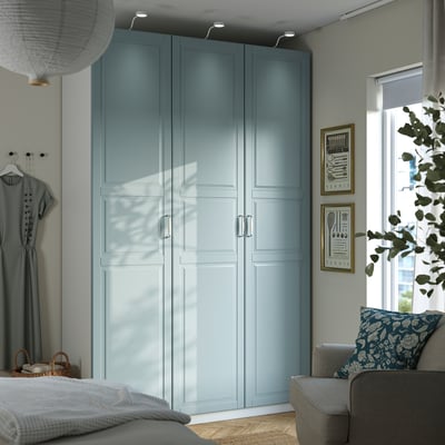 Modernes Schlafzimmer mit hohem grau-blauem PAX-Kleiderschrank, viel Stauraum und stilvoller Einrichtung. Der Kleiderschrank ist der größte Gegenstand im Zimmer.