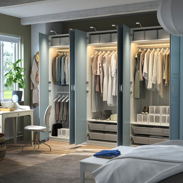Moderner Kleiderschrank PAX mit offenen Türen, die organisierte Kleidung auf Kleiderbügeln, beleuchteten Regalen und Aufbewahrungsboxen freigeben.