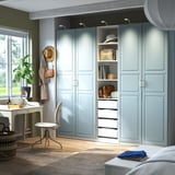 Großer hellblauer PAX-Kleiderschrank, höher als Schreibtisch und Stuhl, mit offenen Regalen, Hut und Geldbörsen.