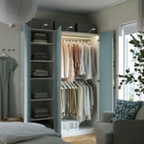 Offener Kleiderschrank, in dem ordentlich gefaltete Kleidung auf Regalen und hängende Kleidungsstücke ausgestellt sind, und organisierter Stauraum mit integrierter Beleuchtung.
