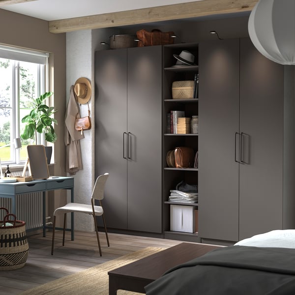 Modernes Schlafzimmer mit grauem PAX-Kleiderschrank, Holzbalken, Schreibtisch und Pflanzen.