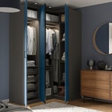 Modernes Schlafzimmer mit offenem blauem PAX-Kleiderschrank mit organisierter Kleidung, Regalen und Aufbewahrungsbehältern. Eine hölzerne Kommode und ein runder Spiegel sind ebenfalls sichtbar.