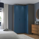 Modernes Schlafzimmer mit blauem PAX-Kleiderschrank, schwarzen Griffen, Holzkommode, weißem Bett und dunkelblauer Wand.
