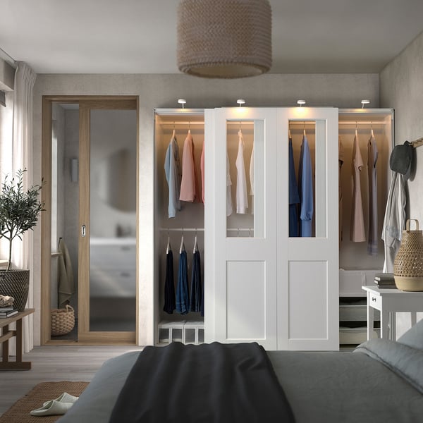 Modernes Schlafzimmer mit großem weißem Kleiderschrank, Glastüren und einem gemütlichen Bett.