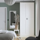 Modernes Schlafzimmer mit großem weißem PAX-Kleiderschrank, hohem Spiegel und salbeigrünen Wänden.