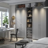 Großer grauer PAX-Kleiderschrank mit offenen Regalen und Schubladen, mit Netzkorb, integrierter Beleuchtung und einem Schreibtisch aus Holz.