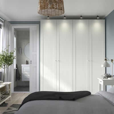 Modernes, minimalistisches Schlafzimmer mit großen weißen PAX-Kleiderschränken, einem schlanken schwarzen Bett und stilvoller Einrichtung.