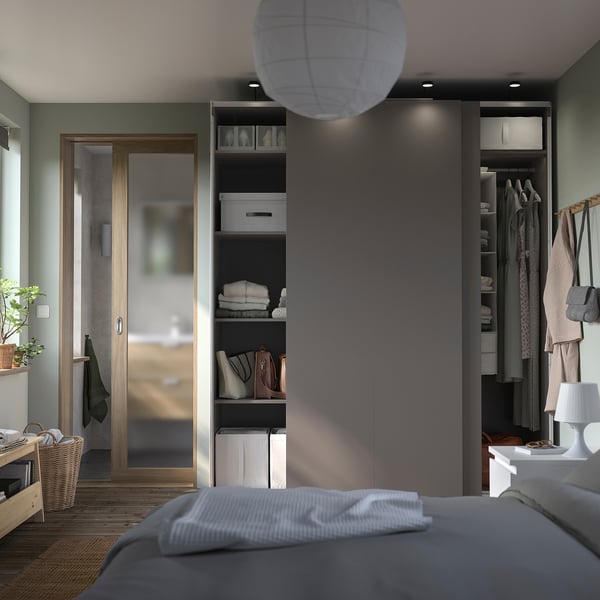 Modernes Schlafzimmer mit grauem Kleiderschrank, Holzboden, Pflanzen.