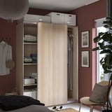 Modernes Schlafzimmer mit PAX-Kleiderschrank aus Holz, Schiebetüren, Regalen mit Kleidung, roten Wänden.